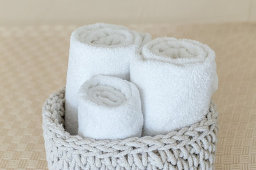 Fototapeta na wymiar Rolled soft towels in basket on white background. Сlose up.