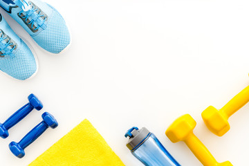 Athletics background with dumbbells, towel, sneakers on white background top view copy space