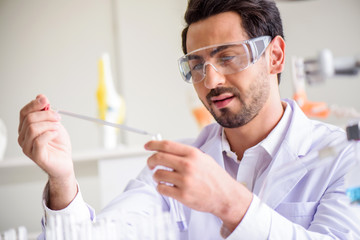 Attractive happiness scientist man lab technician assistant analyzing sample in test tube at laboratory. Medical, pharmaceutical and scientific research and development concept.