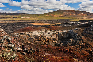 Beautiful colourful Icelandic landscape lava fields mountain geysers zigzag road and moss-covered stones Namafjall, Iceland.