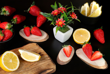 Fresh strawberries on a wooden table with cut lemons 