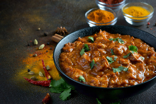 chicken curry with spices on a dark background