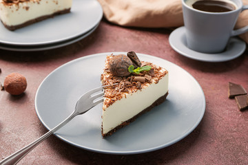 Plate with piece of tasty chocolate cheesecake on color background