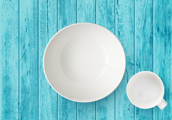 top view of empty white plate and cup isolated on blue wood table