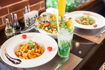 A table of Italian pasta served with salad and fresh drinks
