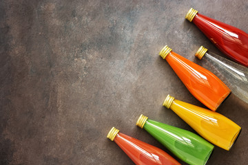 Assorted various colored juices in bottles on a dark background, corner border. Top view, flat lay. Juice - dragon fruit, orange, kiwi, carrot, guava and tomato.