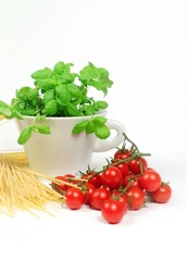close up of spaghetti, tomatoes and a cup with basil on the white background