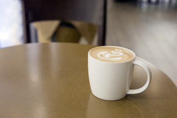 a cup of late art coffee on cafe table