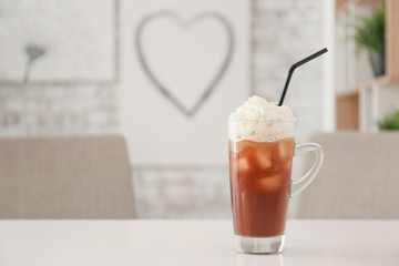 Glass cup of tasty iced coffee on table in cafe