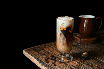 Glass cup of tasty iced coffee on dark background