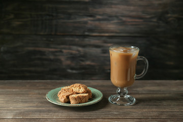 Glass cup of tasty iced coffee with cookies on wooden background