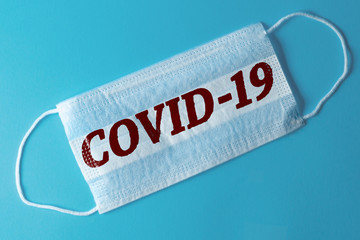 White medical mask with the inscription COVID-19, blue background