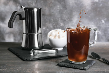 Splashing of coffee in glass cup on dark background