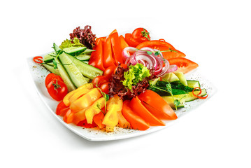 Sliced vegetables on a plate on a white background. Assorted fresh vegetables.