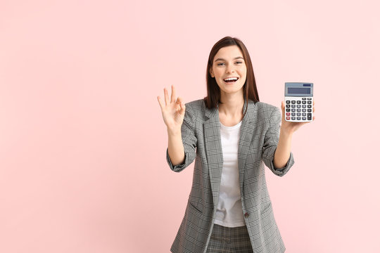 Young woman with calculator showing OK on color background