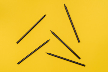 Black pencils on a yellow background. Minimalism