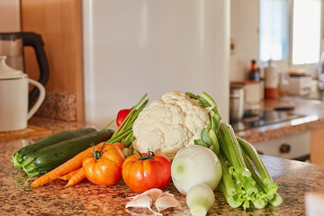 Ingredients for Italian vegetable soup. Celery, tomato, onions and carrots, cauliflower and garlic, zucchini on a table in the kitchen.