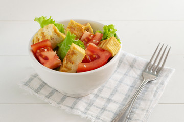 Salad with fried tofu, tomato, lettuce and sesame seeds. Healthy eating concept. Vegetarian salad.