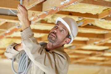 professional builder installing new cables into roof