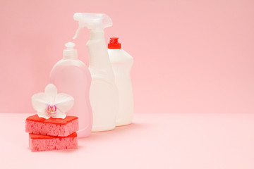 Bottles of washing liquid and sponges on pink background.