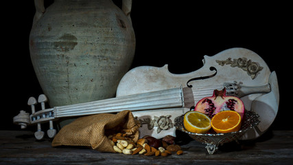 ein Stillleben mit einer Geige, Granatapfel, Cashewkerne, Kastanien und Orangen