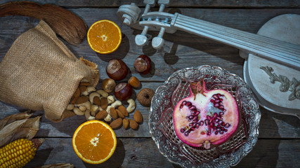 ein Stillleben mit einer Geige, Granatapfel, Cashewkerne, Kastanien und Orangen