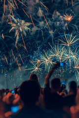 Abstract blurred unrecognizable crowd of young people back to us at holiday fireworks, picturesque...