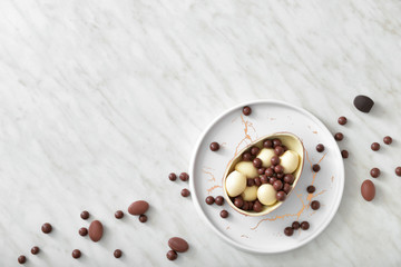 Plate with chocolate eggs and candies on light table