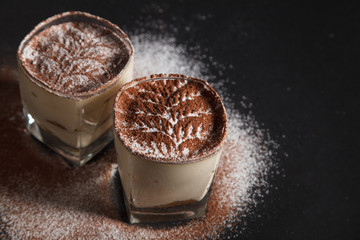 Traditional italian dessert tiramisu on glass on the black background
