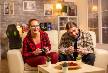 Gamers couple playing video games on the TV with wireless controllers in hands