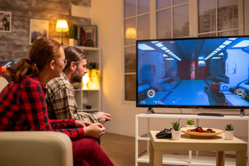 Couple playing video games on big screen TV in the living room late at night