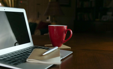 Computer laptop with notepad and coffee on wood table. Work at home concept.