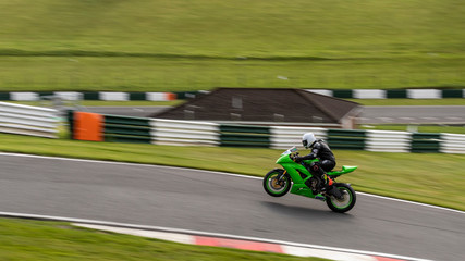 A panning image of a green racing bike passing on one wheel.