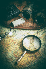 Magnifying glass and binoculars on the old map.