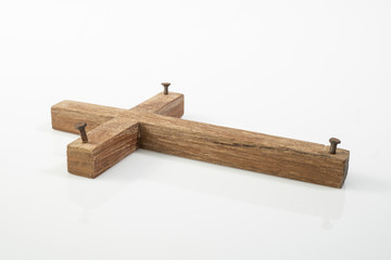 Wooden cross with nails isolated on white background