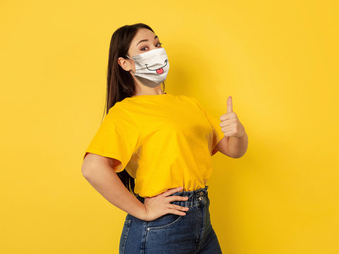 Pointing happy. Portrait of young caucasian woman with emotion on her protective face mask isolated on studio background. Beautiful female model. Human emotions, facial expression, sales, ad concept.