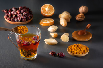 Medicinal herbal tea in a glass cup, ginger, walnut, turmeric, honey, lemon and dry rosehip berries - a means to increase immunity from the virus