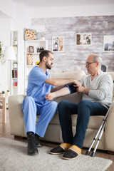 Fototapeta premium Young male doctor in nursing home taking blood pressure