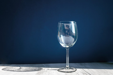 empty wine  glass, natural sunlight with hard shadows and sunbeams, grey and blue double background. Abstract concept of drink