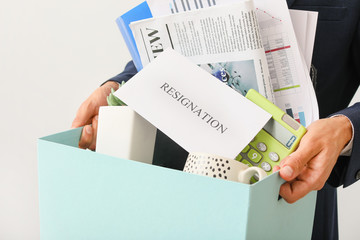 Fired worker with personal things on light background