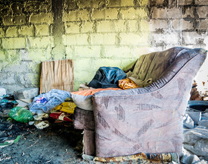 Homeless shelter in Bucharest, Romania. Old broken couch with ashes in front of it, and plastic...