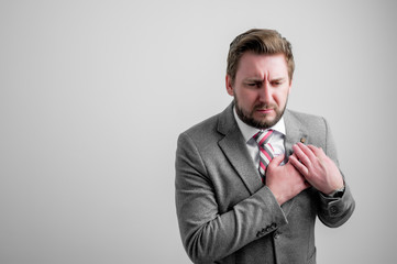 Portrait of business man wearing business clothes with his hand on his chest suffering from acute...