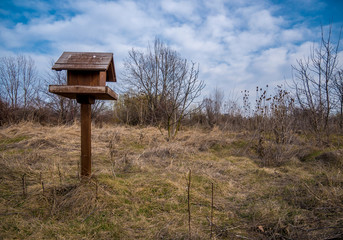 Wooden bird feeder with blue sky in the background. a bird feeder in the shape of a house in a park in Bucharest.