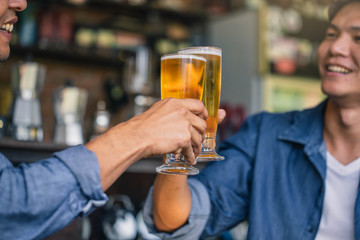 Happy friends drinking and toasting beer at brewery bar restaurant. Friendship concept with young people having fun together at cool vintage restaurant.