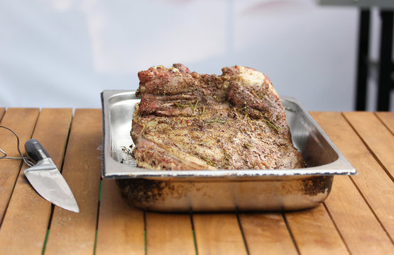 Grilled rack of lamb with knife. Fried meat on a wooden board on a light wooden table. Background image, copy space