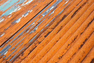 Closeup of rusty metal roof with damaged elements and peeled off paint