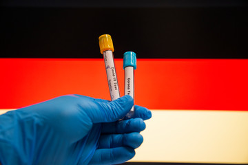 Coronavirus or Covid-19 in the Germany, sample blood tube in hand with Germany flag on background