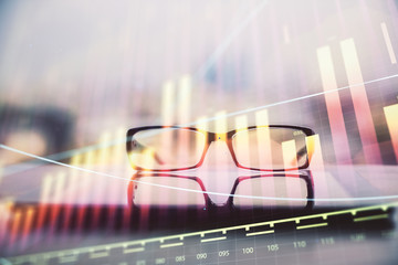 Financial graph hologram with glasses on the table background. Concept of business. Double exposure.