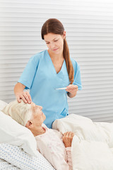 Krankenschwester beim Fieber messen einer Seniorin