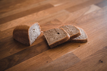 Rustic crusty loaves of bread on wooden plate. Bakery concept with cut sliced homemade bread. Sliced bread on a wooden cutting board.